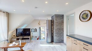 Eine moderne Küche mit einer Wand aus Stein, einer großen Uhr und einem Fernseher im oberen Bereich des Lofts.