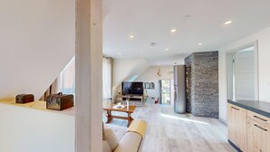 Ein moderner Loft mit einer Küche, einem Essbereich und einem großen Fernseher.