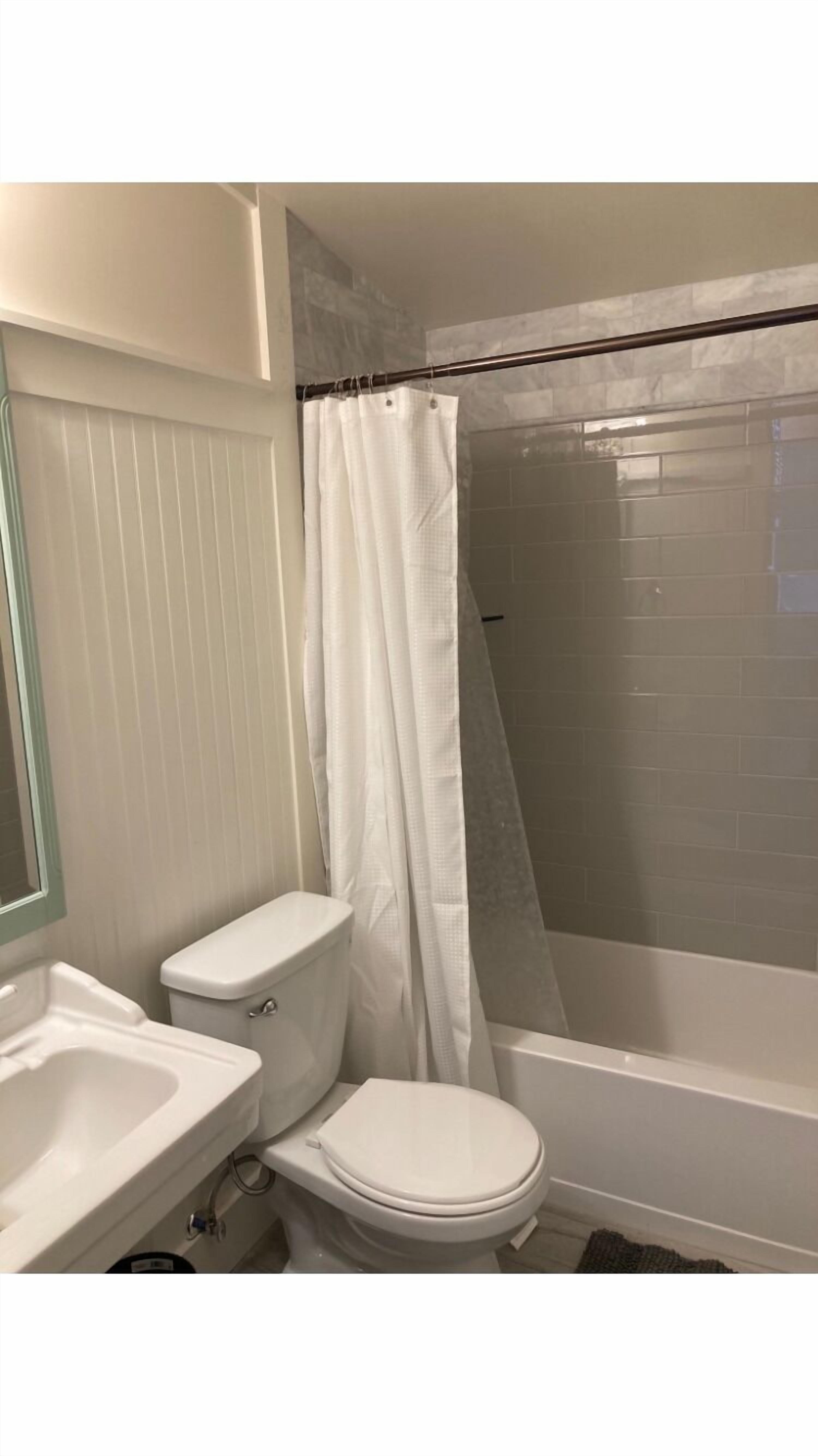Un baño con inodoro, lavamanos y zona de ducha con puerta de cristal.