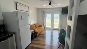 Un espacio habitable compacto con kitchenette, un sofá, comedor y vistas al exterior.