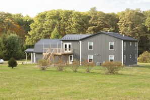 Un bâtiment à deux étages, doté d’un toit en métal, d’une terrasse en bois et d’une grande pelouse à l’avant.