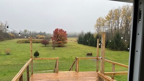 Une terrasse en bois offrant une vue sur un champ verdoyant et des arbres.