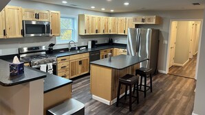 Une cuisine moderne avec des meubles en bois, des appareils électroménagers en acier inoxydable et un îlot central doté de tabourets.