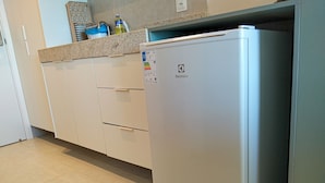 Una cucina con un frigorifero bianco, un piano di lavoro con dispenser d'acqua e un pavimento piastrellato.