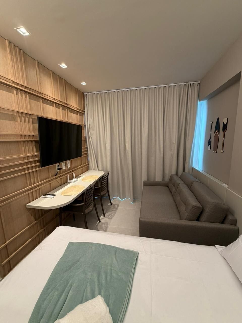 A modern hotel room with a bed, a desk, and a sofa.