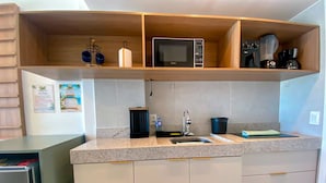 Una cucina con un forno a microonde, una macchina da caffè e un lavello.