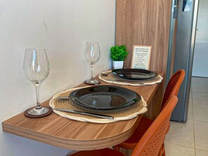 A dining table set with plates, cutlery, and wine glasses, with a sign on the wall. - Mahrak Villa Maracaipe (Ipojuca)