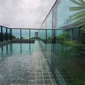 An indoor infinity pool with a view of the ocean, surrounded by glass walls and a tiled floor. - Mahrak Villa Maracaipe (Ipojuca)