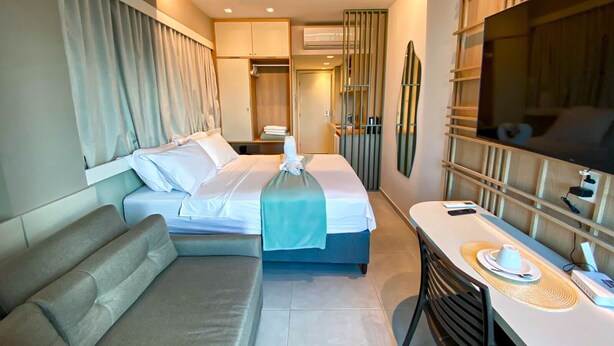 Una camera d'albergo con un letto, un'area salotto, una scrivania e una televisione.