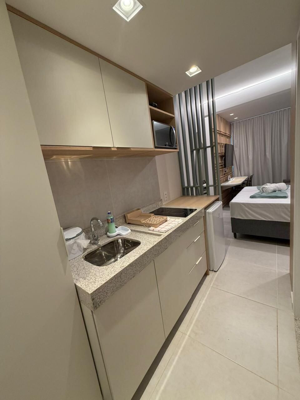 A modern kitchen with a built-in microwave, a sink, and a compact refrigerator.