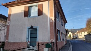 Un bâtiment à deux étages, doté d’une porte et de fenêtres, d’un mur en pierre et surplombant un ciel dégagé.