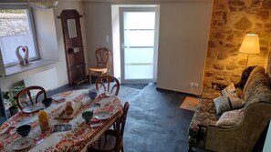 A dining area with a table set for two, a stone wall, a sofa, and a lamp. - Holiday Home 'La Maison De Béatrice' with Mountain View, Private Terrace and Wi-Fi (Oberbruck)