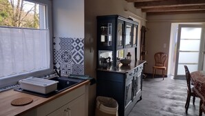 Une cuisine équipée d’un évier, d’un placard et d’un coin repas avec des chaises et une table.