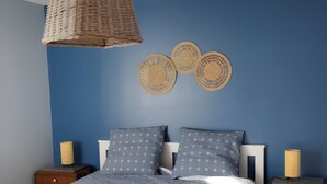 Une chambre à coucher comprenant un lit, deux tables de chevet, une lampe suspendue et des éléments de décoration murale.