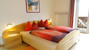 Une chambre à coucher comprenant un lit, des tables de chevet, une commode, une fenêtre avec vue et un tableau au mur.