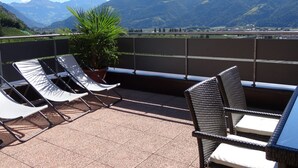 Une terrasse avec deux fauteuils, une plante en pot et une table.