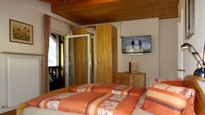 A bedroom with a bed, wooden headboard, a television on the wall, a dresser, and a radiator. - Apartment 'Lichtnelke' with Mountain View, Shared Pool and Wi-Fi (Naturno)