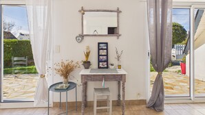 Ein Zimmer mit einem Holzbüro, einem Sessel, einem Spiegel und einem kleinen Tisch mit einer Vase und Dekorationselementen.