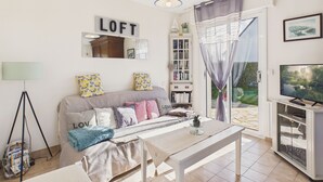 Ein Wohnzimmer mit einer Couch, einem Couchtisch, einem Bücherregal, einem Fernseher und einem großen Fenster mit Vorhängen.