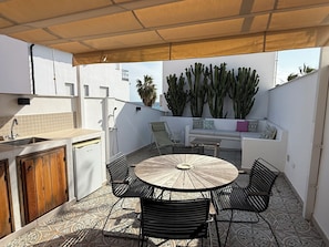 A sunlit outdoor patio with a round table and chairs, a built-in bench, a sink, and a shower. - Casa Las Brisas - Rooftop Terrace & Sea View - Mediterranean cozy Townhouse (Algarrobo-Costa)