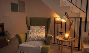 A cozy living room with a green armchair, patterned pillow, a small table with a candle, a glass of red wine, and a staircase in the background. - Casa Las Brisas - Rooftop Terrace & Sea View - Mediterranean cozy Townhouse (Algarrobo-Costa)