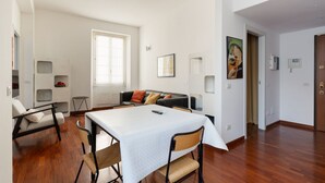 A modern living room with a dining table, sofa, and a small side table. - GuestHost - Cozy 50m2 apartment, perfect for 2 people, located on the first floor of a building with lift.The accommodation is located in the Derganino area, about 600 meters from the Lancetti railway station and just over 1 km from the Maciachini  (Milan)