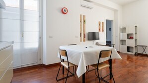 A dining area with a table set for four, a flat-screen TV mounted on the wall, and a whiteboard. - GuestHost - Cozy 50m2 apartment, perfect for 2 people, located on the first floor of a building with lift.The accommodation is located in the Derganino area, about 600 meters from the Lancetti railway station and just over 1 km from the Maciachini  (Milan)