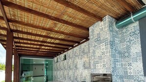 A modern kitchen with a tiled backsplash, wooden flooring, and a built-in oven. - Casa Parque das Árvores - Camaçari - BA (Camaçari)