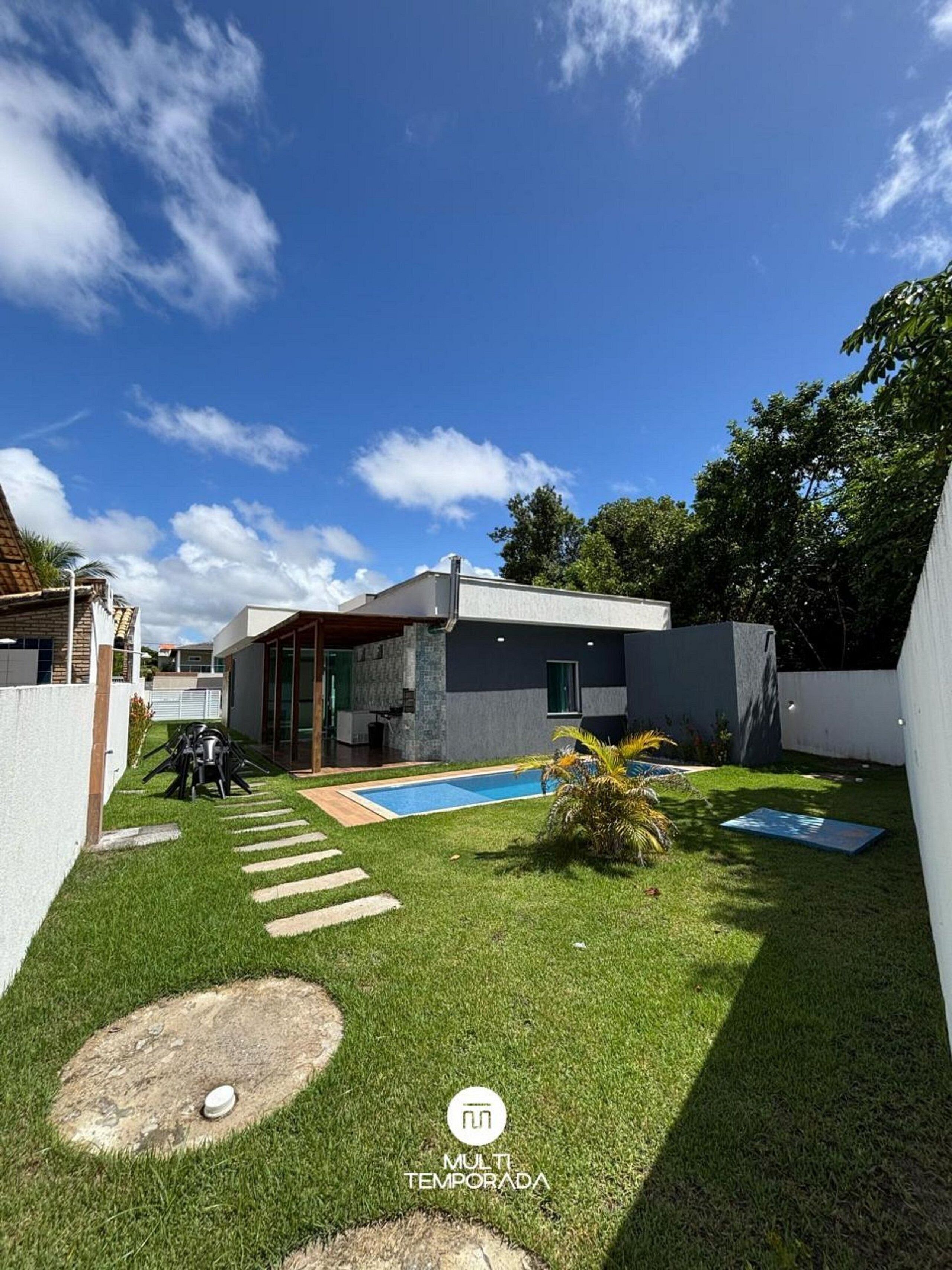 A modern house with a swimming pool, a well-maintained lawn, and a patio area.