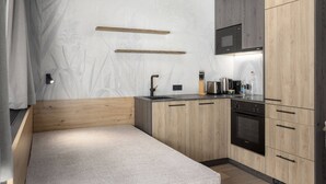 Een compacte keuken met houten kastjes, een inbouwmagnetron en een klein aanrecht.