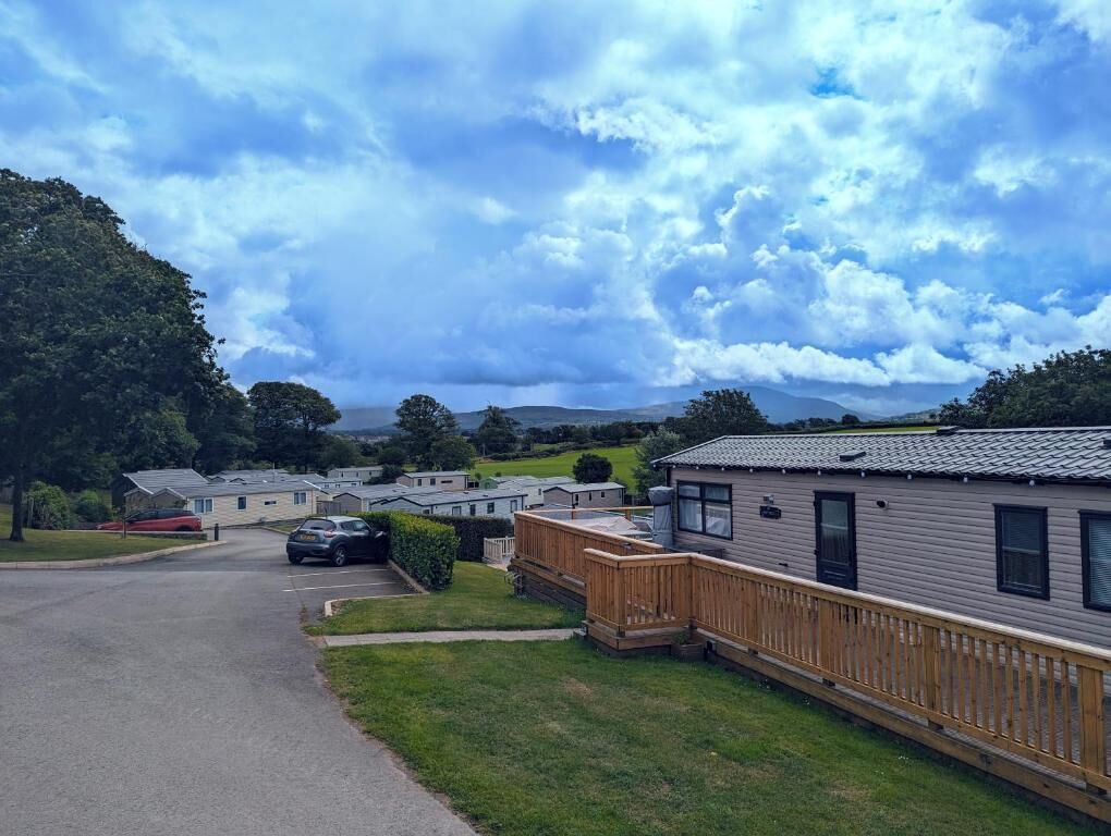 A row of mobile homes with a paved driveway and a grassy area in front.