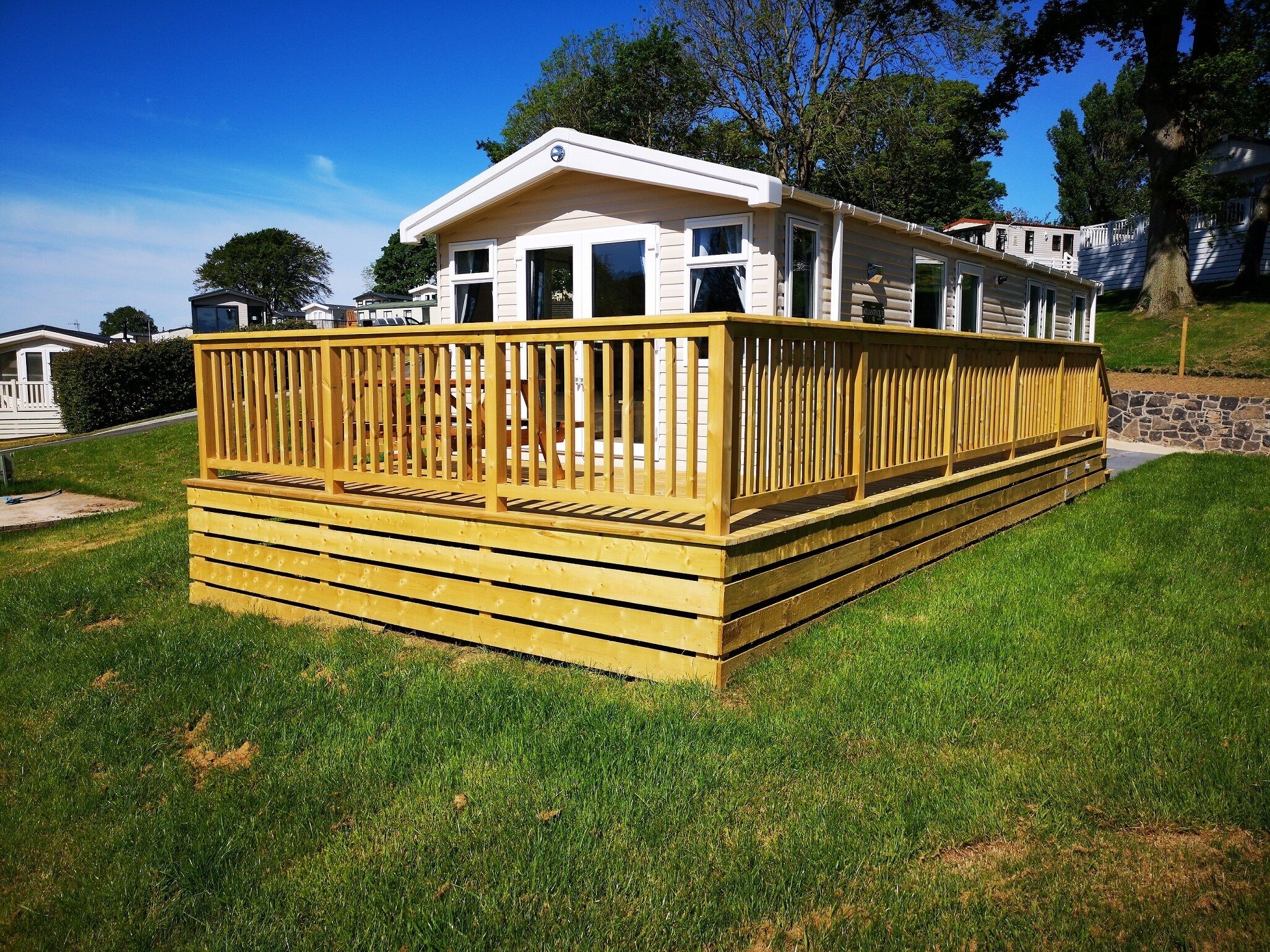 A mobile home with a wooden deck and a front porch.
