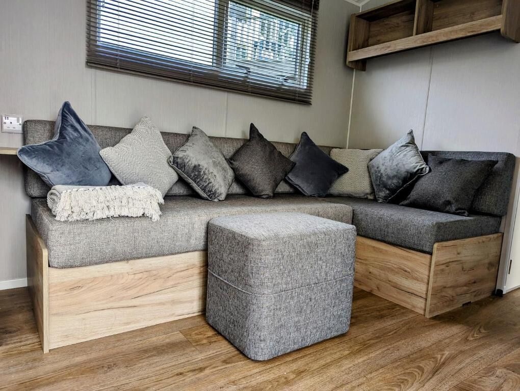 Una sala de estar moderna con un sofá seccional gris, un reposapiés gris y una mesa de centro de madera.