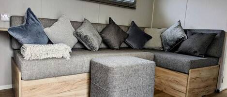Una sala de estar moderna con un sofá seccional gris, un reposapiés gris y una mesa de centro de madera.
