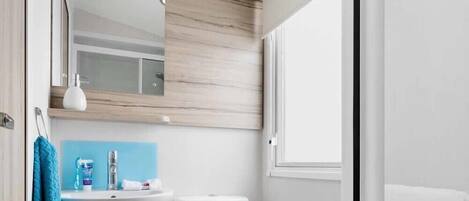 A compact bathroom with a white sink, toilet, and mirror.