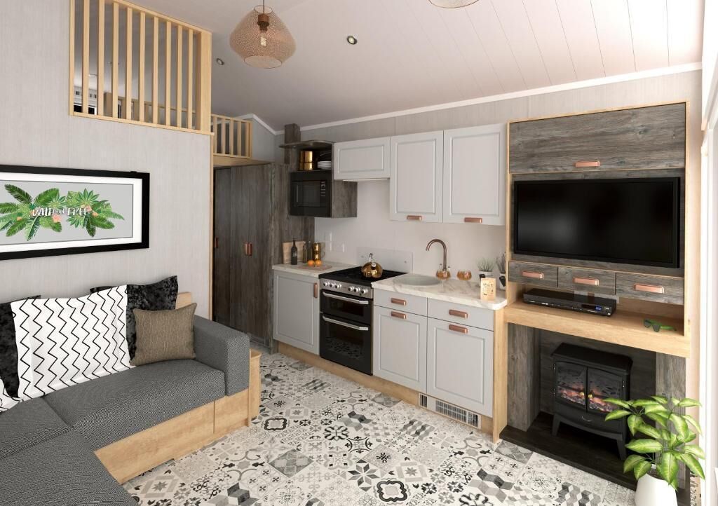A modern kitchen with white cabinets, a black stove, and a large TV.