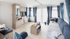 A modern living area with a sofa, a coffee table, and a TV. - Coed Helen Holiday Park (Caernarfon)
