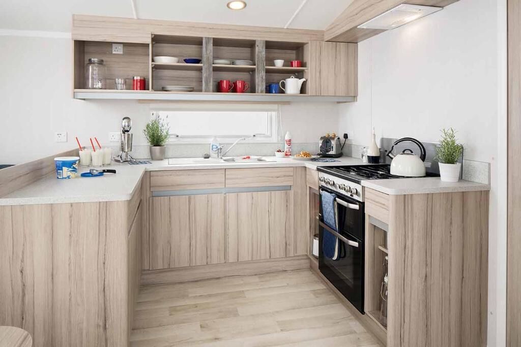 Une cuisine moderne avec des meubles en bois, un four encastré et un plan de travail sur lequel sont disposés divers ustensiles de cuisine.