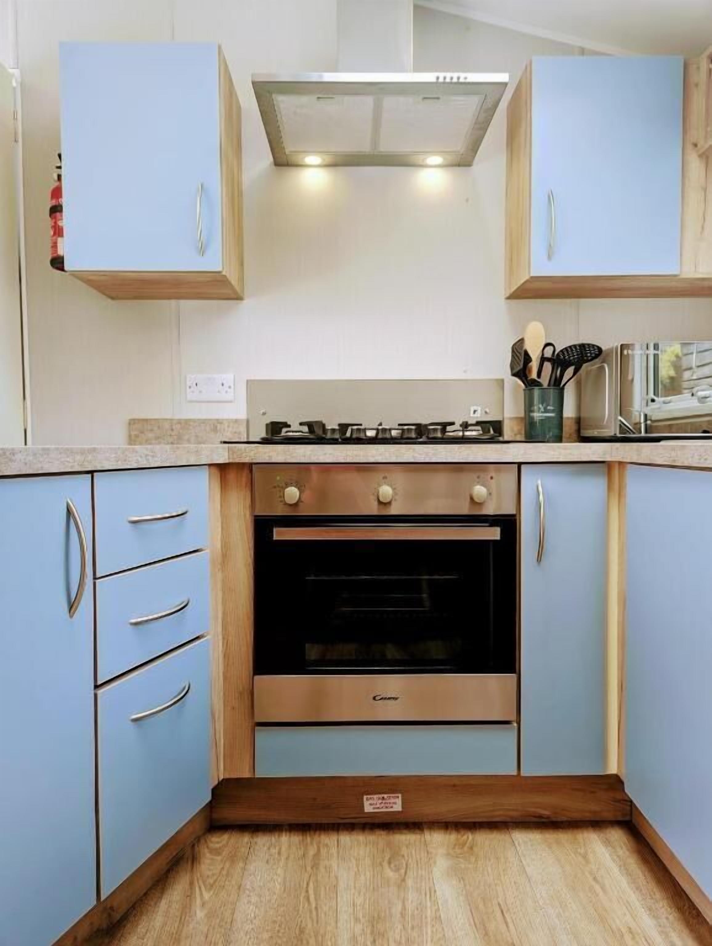 A kitchen with light blue cabinets, a stainless steel stove, and a built-in oven.