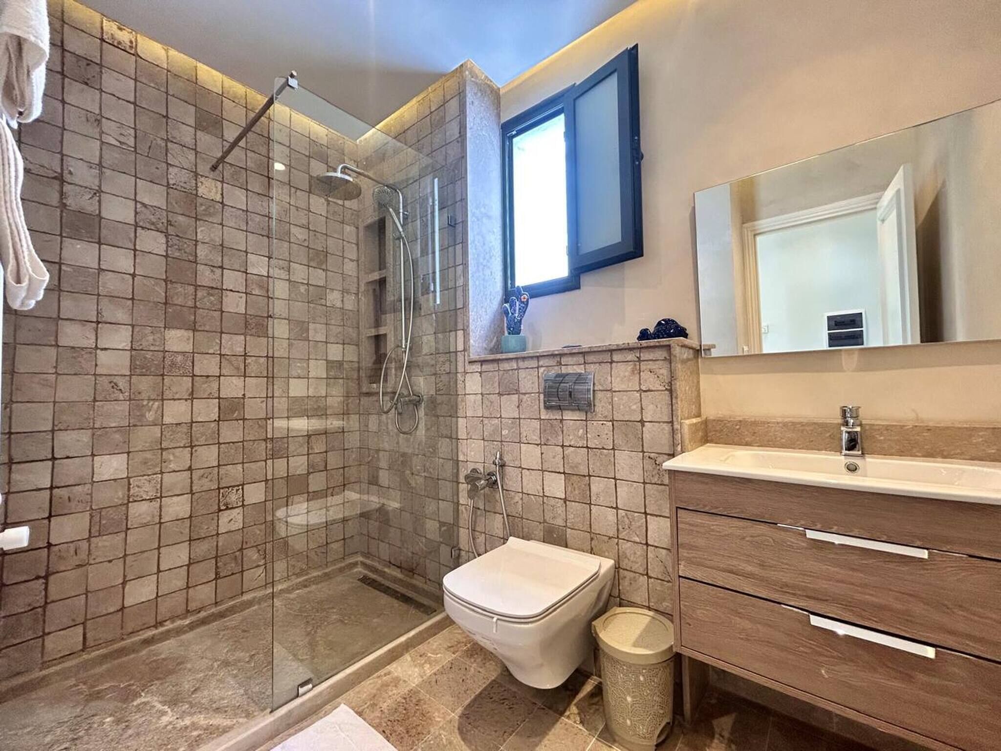 Une salle de bain avec une douche à parois de verre, des toilettes et un meuble-lavabo avec un miroir.