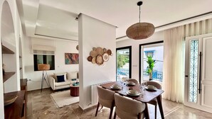 Un comedor con una mesa preparada para cuatro personas, un sofá, una lámpara de pie y un adorno en la pared.