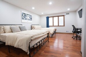 Quarto com duas camas, uma escrivaninha e uma janela.