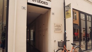 Entrada de um edifício com uma placa que diz 'STUDDED' e uma bicicleta estacionada na frente.