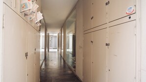 Um corredor com armários, um mural com papéis e uma porta no final.