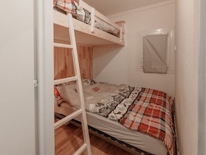A bunk bed room with a wooden ladder, a window with a white blind, and a patterned bedspread. - Apartment for 4 people, balcony, mountain view (Morillon)