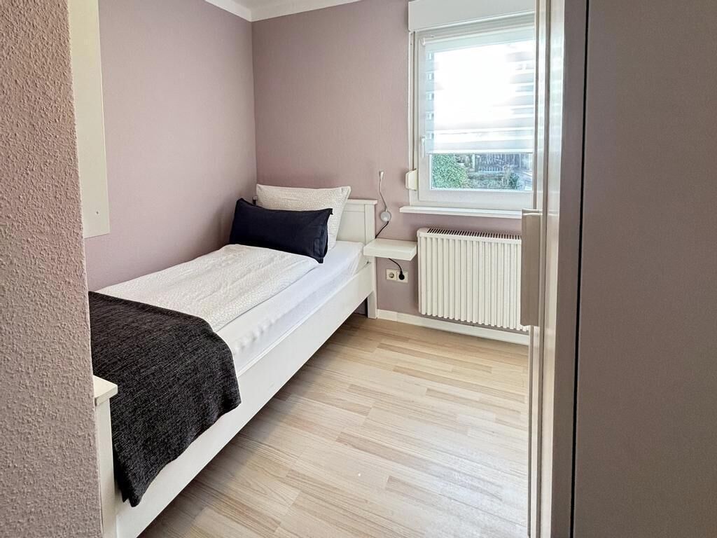 A bedroom with a bed, a window, and a radiator.