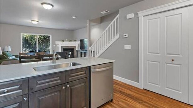 A modern kitchen with a built-in dishwasher, a wooden floor, and a white staircase. - Modern 3BR Salem Retreat in Quiet Neighborhood (Salem)