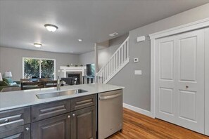 A modern kitchen with a built-in dishwasher, a wooden floor, and a white staircase. - Modern 3BR Salem Retreat in Quiet Neighborhood (Salem)