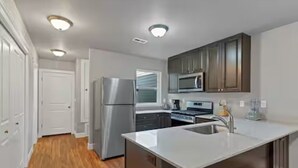 A modern kitchen with stainless steel appliances, a central island with a sink, and wooden cabinets. - Modern 3BR Salem Retreat in Quiet Neighborhood (Salem)