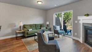 A modern living room with a green sofa, a blue armchair, and a fireplace. - Modern 3BR Salem Retreat in Quiet Neighborhood (Salem)